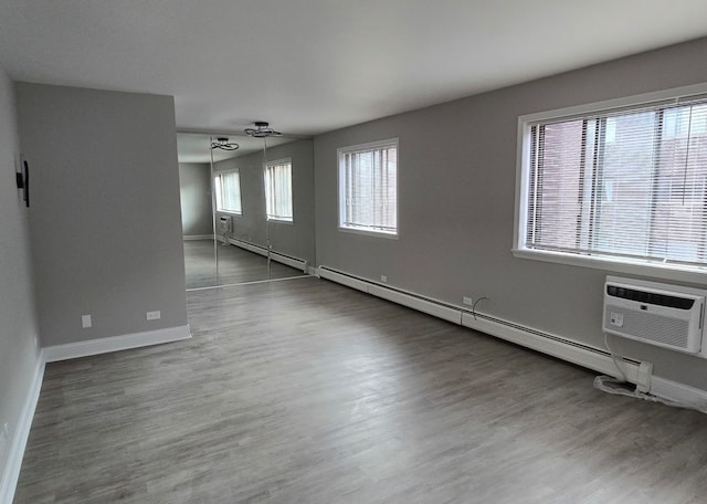 spare room featuring a wall mounted air conditioner, dark hardwood / wood-style flooring, and baseboard heating