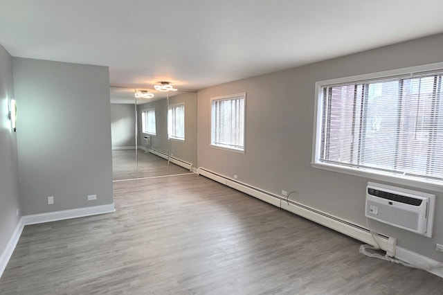 empty room featuring baseboard heating, a wall mounted AC, and dark wood-type flooring