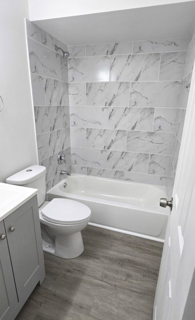 full bathroom featuring hardwood / wood-style floors, vanity, toilet, and tiled shower / bath combo