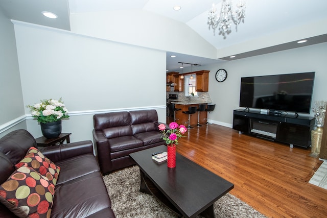 living room featuring vaulted ceiling, dark hardwood / wood-style floors, and a notable chandelier