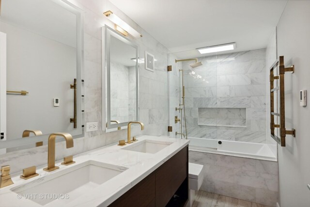 bathroom with hardwood / wood-style flooring, tiled shower / bath combo, and vanity