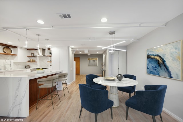 dining space with light wood-type flooring and sink