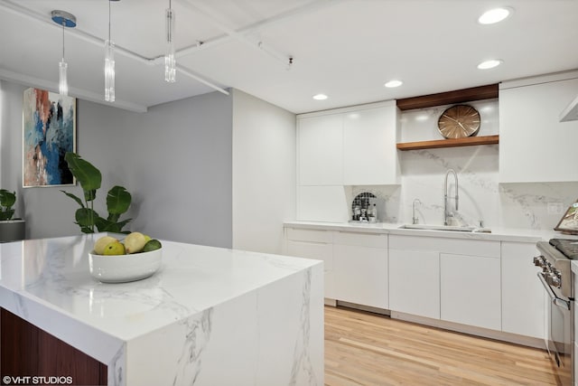 kitchen with white cabinetry, sink, pendant lighting, and light wood-type flooring