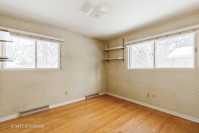 empty room with light hardwood / wood-style flooring and a baseboard heating unit