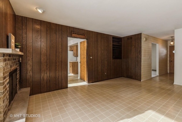 unfurnished living room with a brick fireplace and wooden walls