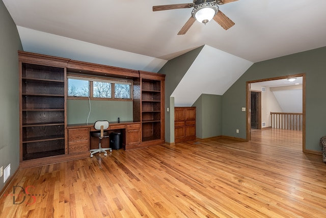 unfurnished office featuring ceiling fan, built in desk, lofted ceiling, and light hardwood / wood-style floors