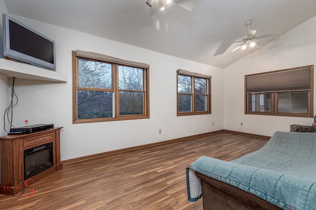 living room with ceiling fan, dark wood-type flooring, and vaulted ceiling