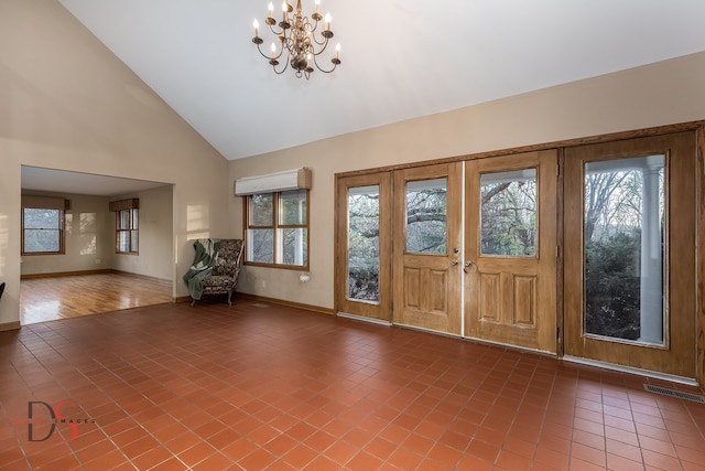 tiled entryway with high vaulted ceiling and an inviting chandelier