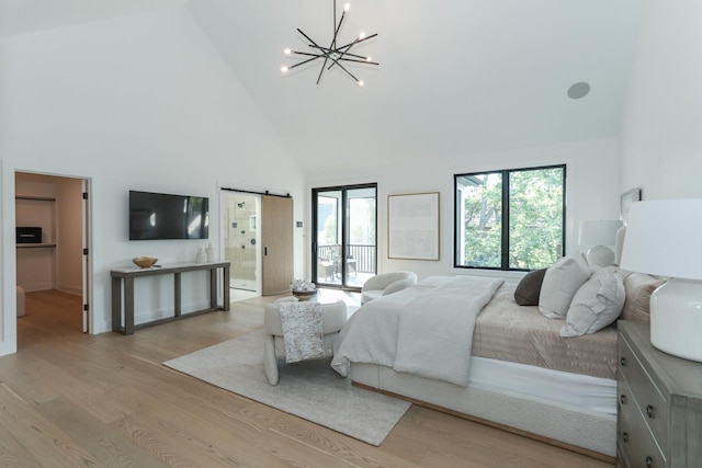 bedroom featuring an inviting chandelier, a barn door, high vaulted ceiling, light hardwood / wood-style flooring, and access to exterior