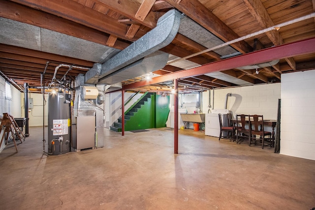 basement featuring heating unit, washer and clothes dryer, gas water heater, and sink