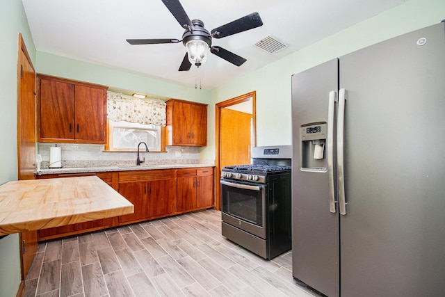 kitchen with sink, ceiling fan, light wood-type flooring, tasteful backsplash, and stainless steel appliances