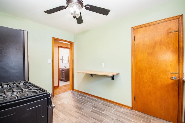 kitchen featuring stainless steel fridge, gas stove, light hardwood / wood-style floors, and ceiling fan