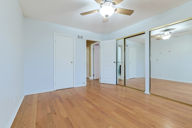 unfurnished bedroom with light wood-type flooring, ceiling fan, and multiple closets