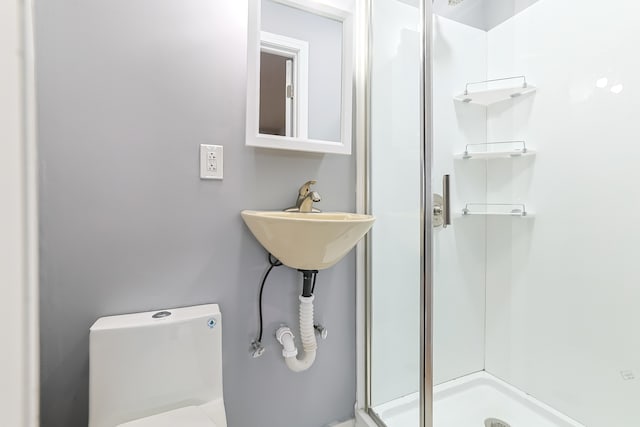 bathroom with an enclosed shower, toilet, and sink