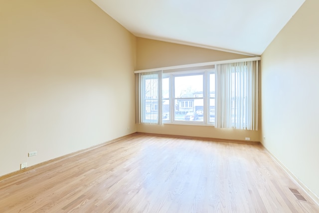 spare room with light wood-type flooring and high vaulted ceiling