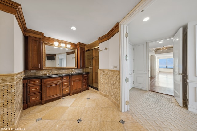 bathroom featuring vanity, a shower with shower door, and ornamental molding