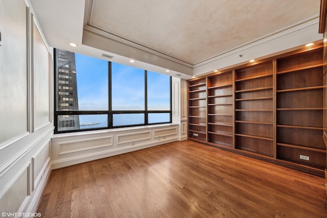 unfurnished room featuring hardwood / wood-style floors, a raised ceiling, and a water view