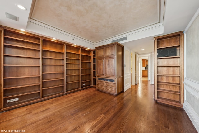 unfurnished living room with dark hardwood / wood-style floors, a raised ceiling, ornamental molding, and built in shelves