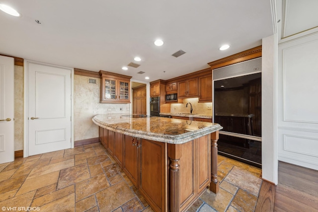180 E Pearson St Unit 4901, Chicago, IL 60611 - kitchen with a sink, black appliances, brown cabinets, a peninsula, and stone tile flooring