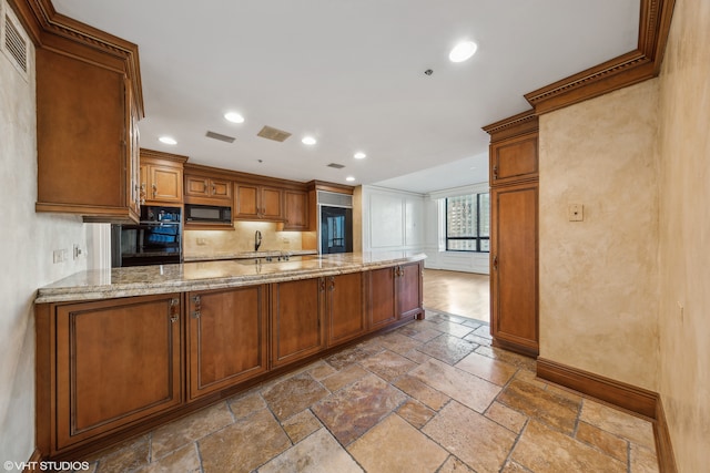 kitchen featuring black appliances, kitchen peninsula, light stone countertops, and sink