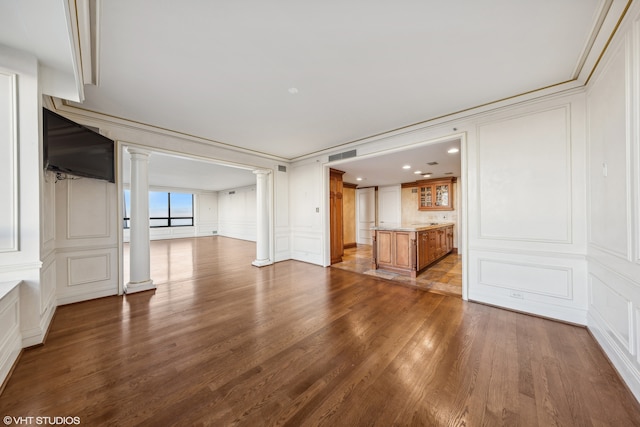 unfurnished living room with decorative columns, crown molding, and wood-type flooring