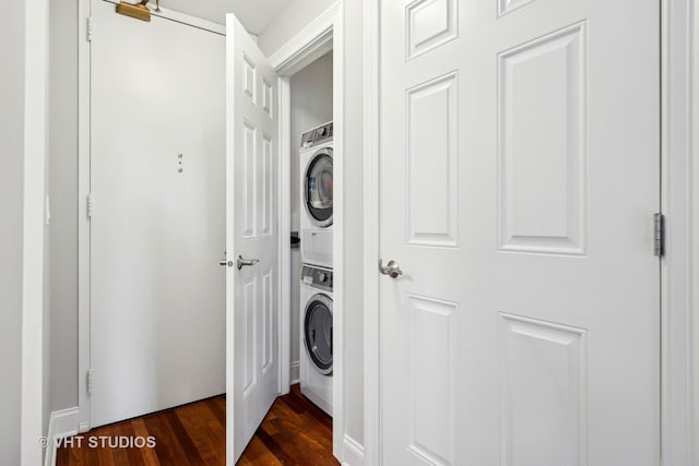 clothes washing area featuring stacked washer and dryer and dark wood-type flooring