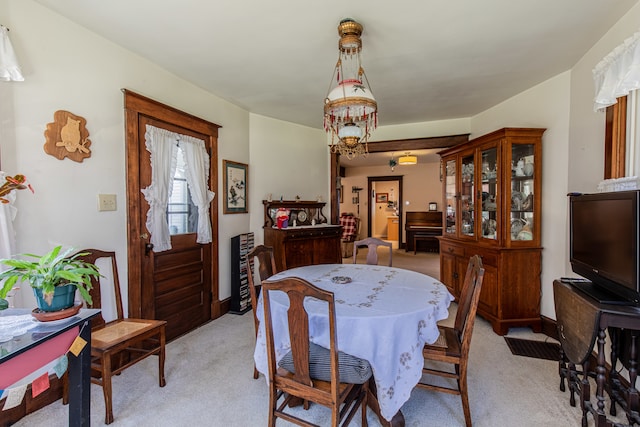 dining room featuring light carpet and a chandelier