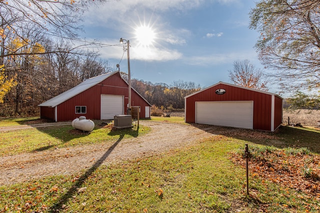 view of outbuilding with a garage, a lawn, and central air condition unit