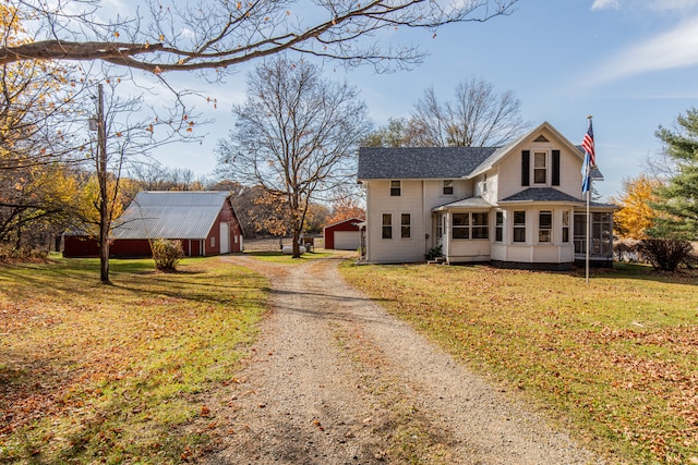 view of front of home with a sunroom, an outbuilding, a front lawn, and a garage