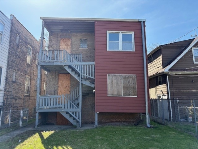 back of house featuring a yard, fence, and stairs