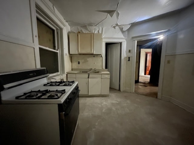 kitchen featuring backsplash, white gas range, and sink