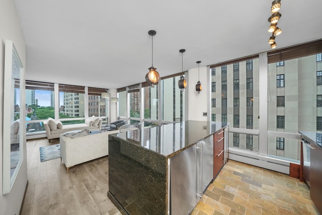 kitchen featuring floor to ceiling windows, a baseboard heating unit, dark stone countertops, light hardwood / wood-style floors, and decorative light fixtures