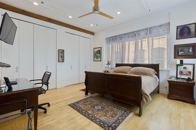 bedroom with light wood-type flooring, ceiling fan, and multiple closets