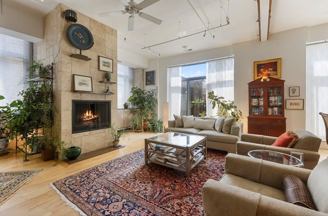 living room featuring hardwood / wood-style floors, ceiling fan, and a tile fireplace