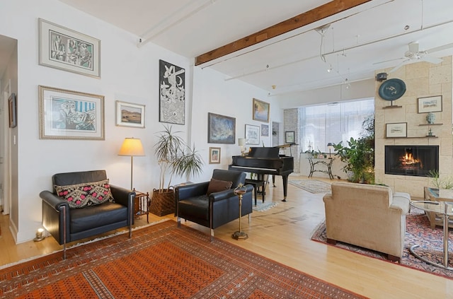 sitting room featuring a tile fireplace, ceiling fan, beamed ceiling, and hardwood / wood-style flooring