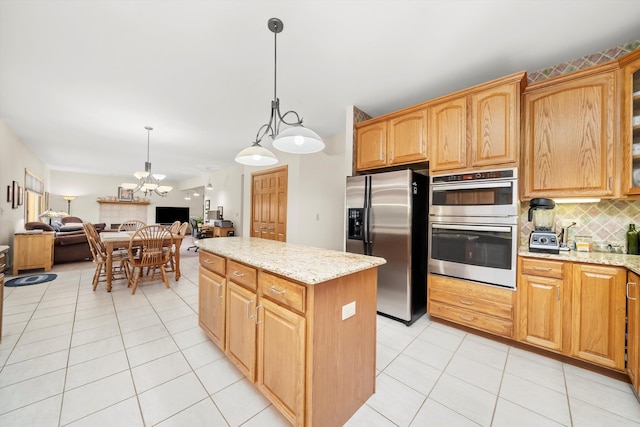 kitchen featuring hanging light fixtures, light stone countertops, a kitchen island, stainless steel appliances, and a chandelier