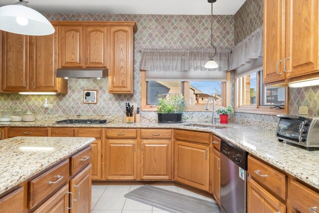 kitchen featuring light stone countertops, sink, pendant lighting, light tile patterned flooring, and appliances with stainless steel finishes