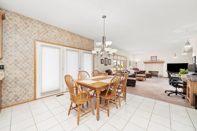 dining area featuring a fireplace, light carpet, and a chandelier