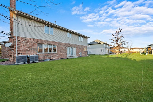 rear view of house featuring central air condition unit and a yard