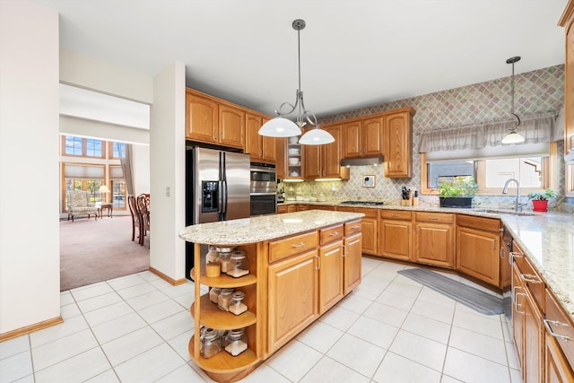 kitchen with sink, hanging light fixtures, appliances with stainless steel finishes, a kitchen island, and light colored carpet