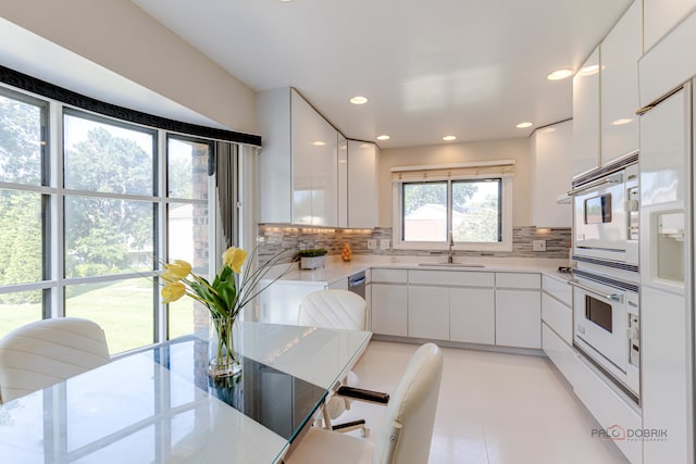 kitchen with white cabinets, white oven, tasteful backsplash, and sink