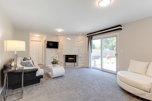 carpeted living room with a stone fireplace