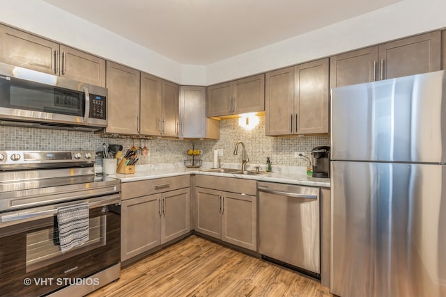 kitchen featuring tasteful backsplash, sink, stainless steel appliances, and light wood-type flooring