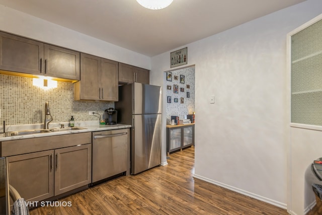 kitchen with wood-type flooring, appliances with stainless steel finishes, decorative backsplash, and sink