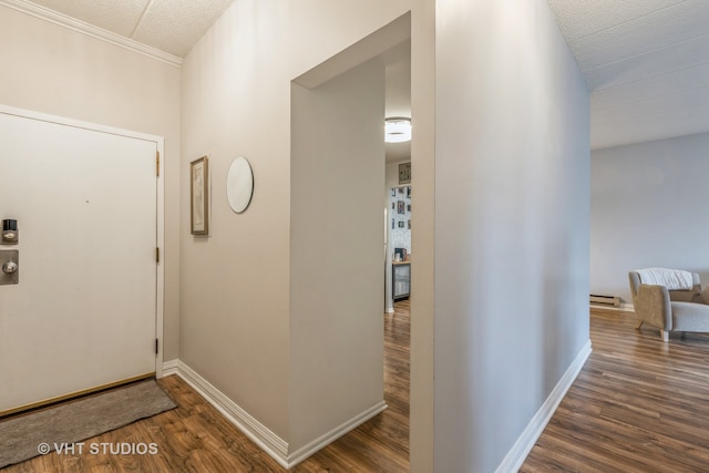 hallway featuring a baseboard heating unit, dark hardwood / wood-style flooring, a textured ceiling, and ornamental molding