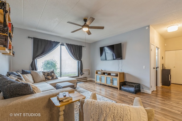 living room featuring ceiling fan, light wood-type flooring, and a textured ceiling