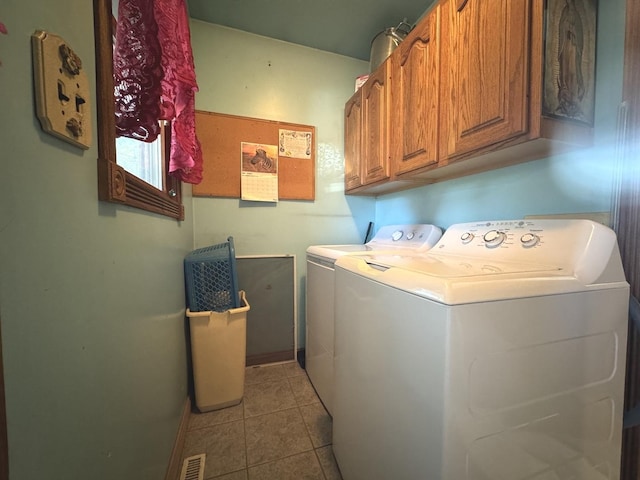 laundry area with washing machine and clothes dryer, light tile patterned flooring, and cabinets