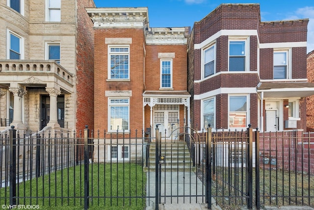 townhome / multi-family property featuring a fenced front yard and brick siding