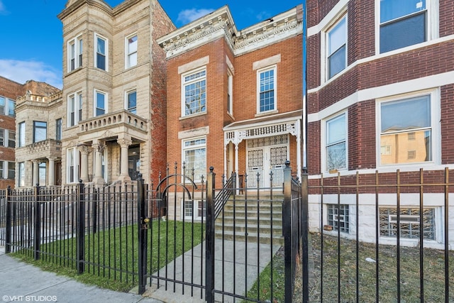 townhome / multi-family property with a fenced front yard and brick siding