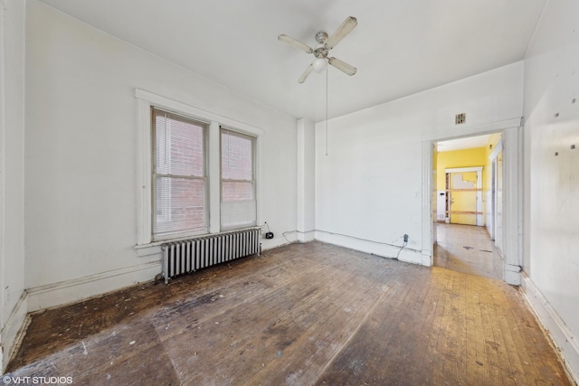 unfurnished room with visible vents, radiator heating unit, a ceiling fan, and hardwood / wood-style floors